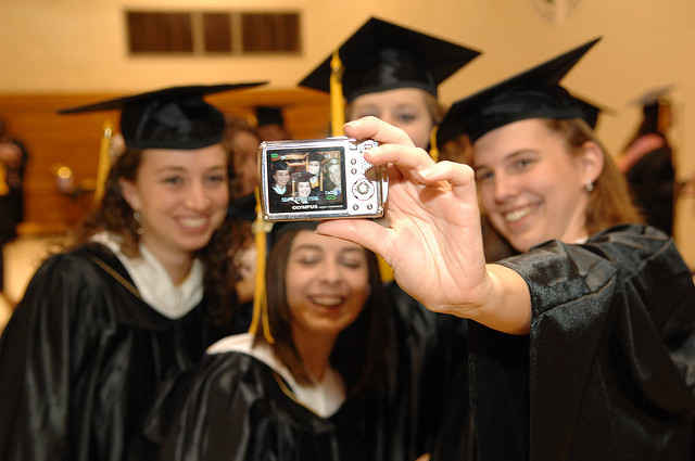 Graduates wearing black cap and gowns taking a selfie