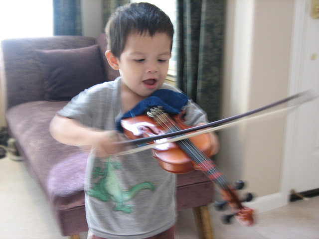 Young boy playing violin happily 