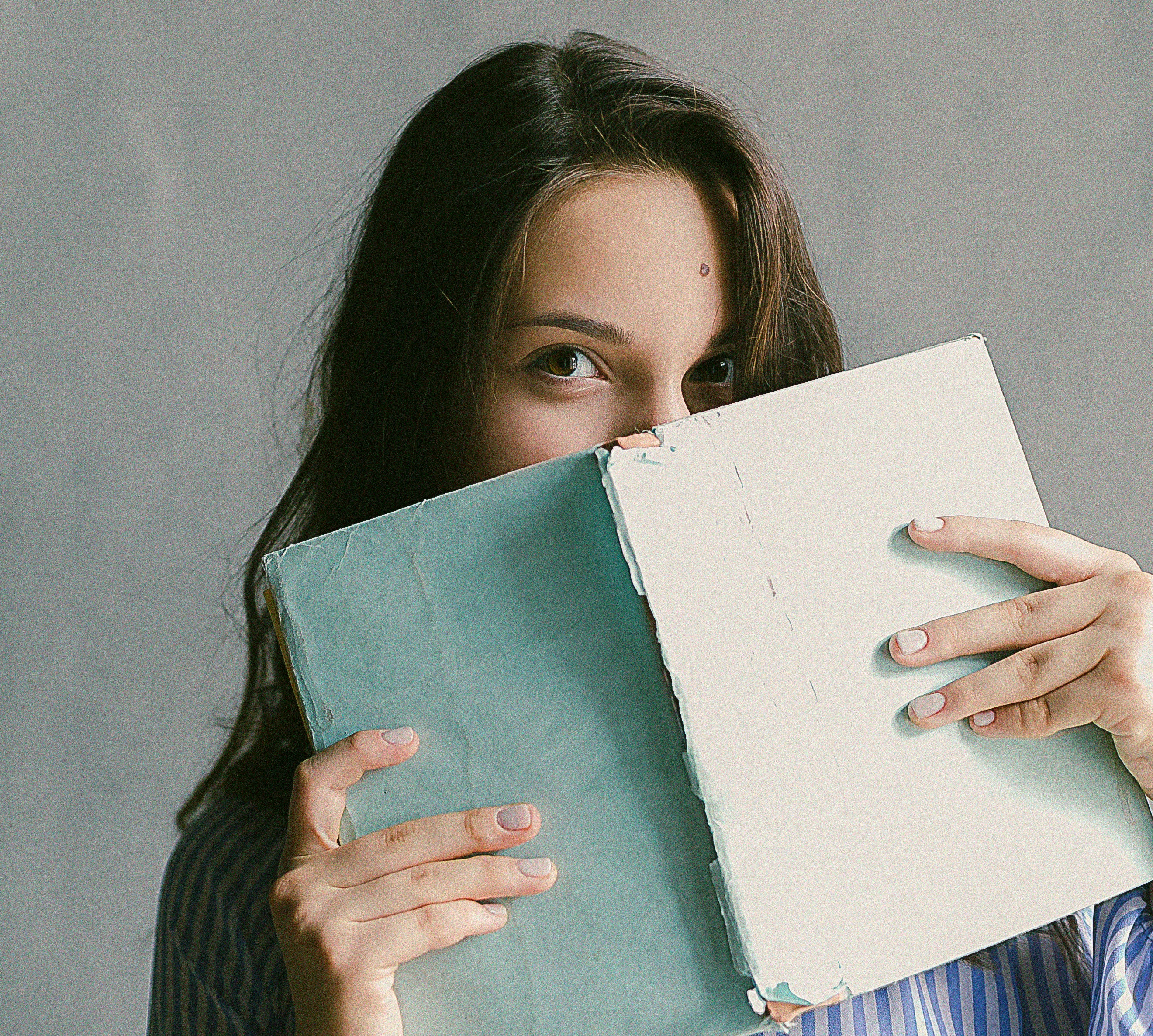 Girl with notebook covering her face