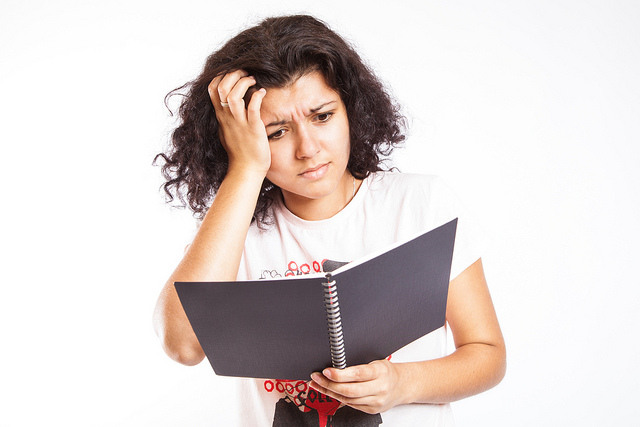 Confused college student looking at notebook 