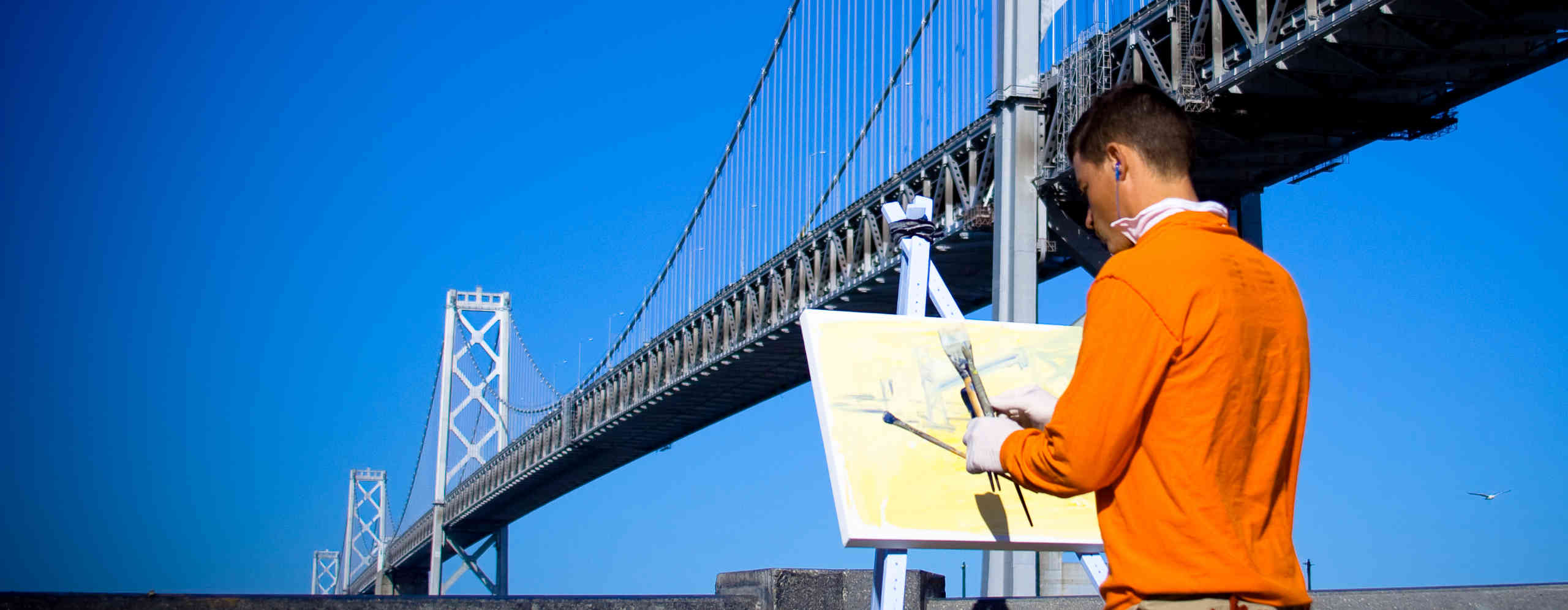 Man painting by the bridge