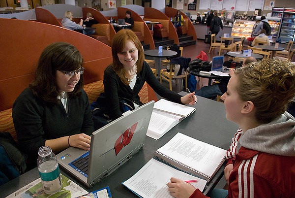 Friends learning online at a college library cafe