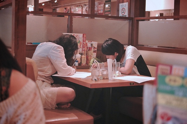 Two girls writing on worksheets.